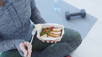 Fitness and Healthy food. Woman is resting and eating a healthy food after a workout in a white in
