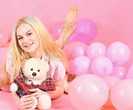 Birthday girl concept. Girl in pajama, domestic clothes lay near air balloons, pink background. Blonde on smiling face