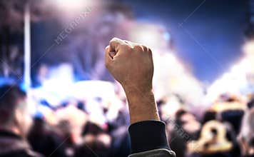 Crowd of people protesting. Protest, uprising, march or strike in city street. Anonymous activist fist up.