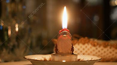 Candle lit on santa claus shape at dinner table christmas night closeup