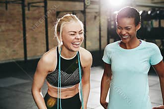 Laughing female friends standing in a gym after working out