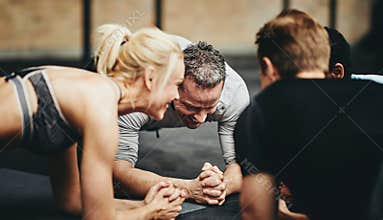 Smiling group of friends planking together during a workout clas