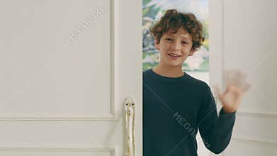 Little caucasian boy entering room waving hand