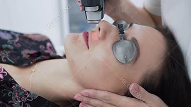 Close-up cosmetologist makes hair laser removal procedure to young woman face at clinic, slow motion