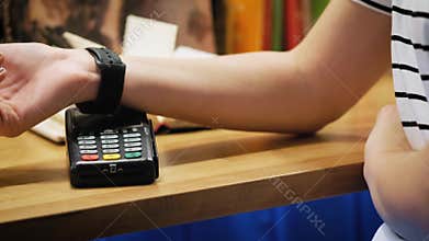 Customer paying with NFC technology by smart watch contactless on terminal in modern cafe