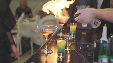 The barman prepares a cocktail and sets it on fire