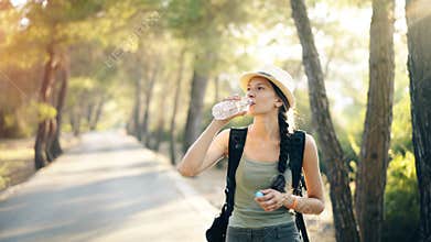 Attractive young tourist girl refreshing by drinking water after backpacker journey