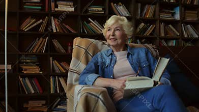 Nice elderly woman sitting in a home library