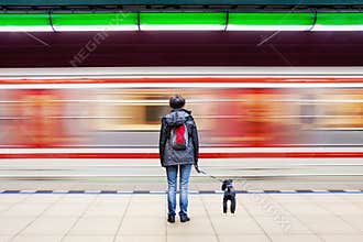 Woman with dog at subway station with blurry moving train