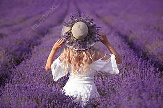 Back view of Young blond woman in lavender field. Happy carefree