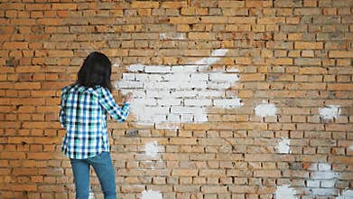 The woman paints a red brick in house in white color