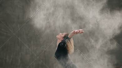 The dancer girl dressed in black body suit perform the contemporary dance on the floor, makes the stroke with the hair