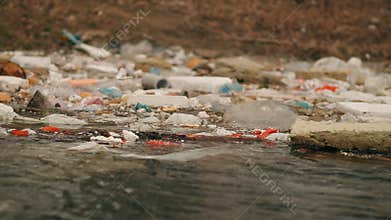 Garbage floats in the water near the shore. Environmental pollution.