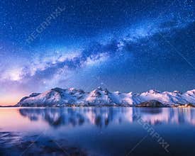 Milky Way over snow covered mountains and sea at night in winter