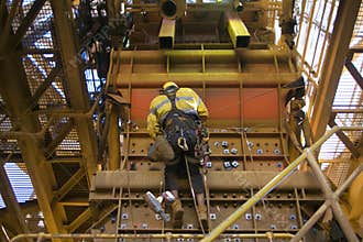 Male rope access industry worker wearing safety harness, fall protection helmet hanging working on Y hang rope position
