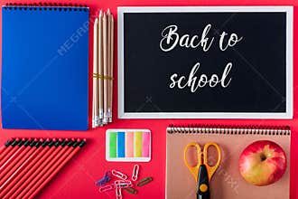 top view of blackboard with lettering back to school apple and arranged variety stationery on red