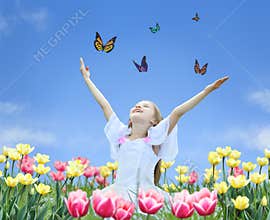 Little girl in tulips with hands up and butterfly