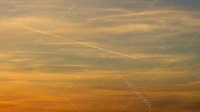 Jet airplane airliner flying leaving vapor trail across sky, clouds and sun at sunset