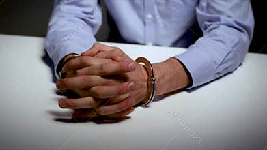 Arrest - hands with handcuffs on the table