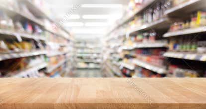 Wood table top on blur of supermarket product shelf background.