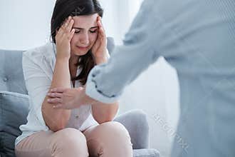 Young woman suffering from depression crying in her therapist`s