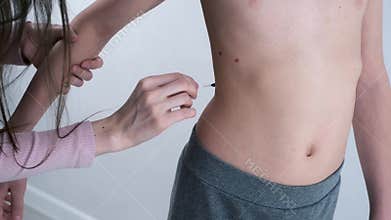 Mom lubricates the rash from chickenpox on her son's body with red antiseptic.