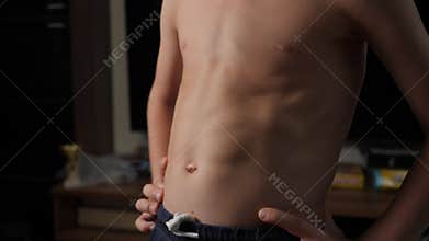 A close-up of a little boy athlete shows the muscles on his stomach.
