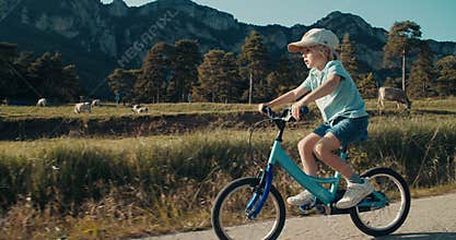 Carefree children cycling bike on country road with mountain. Bicycle at summer