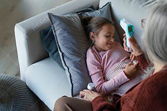 Grandmother taking care of her ill grandchild lying on sofa