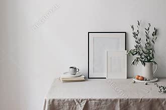 Spring, Easter breakfast still life. Cup of coffee, books and empty picture frames mockups. Linen tablecloth. Olive tree