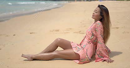 Barefoot ethnic woman sitting on beach