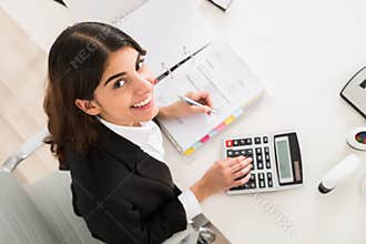 Happy Businesswoman Doing Financial Calculation At Desk
