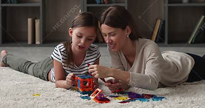 Young mother and little daughter play together creative magnetic constructor