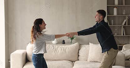 Bonding loving millennial man and woman dancing at home.