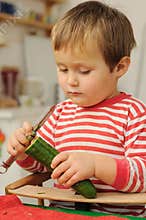 Young child peeling cucumber