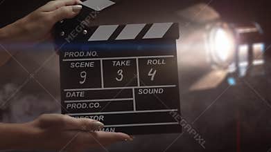 Human hands are using a clapperboard on set. Beginning of scene in film or television production. Concept of