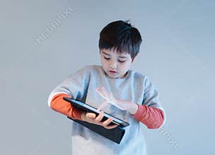 Isolated school boy typing on tablet Authentic portrait of Kid playing game or watching cartoon from digital pad Child playing