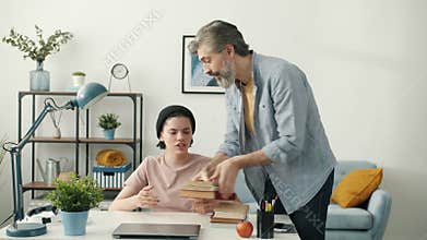 Modern teenager using laptop when father bringing books and taking away computer