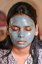 A  beautiful woman wearing face clay mask. casual portrait.