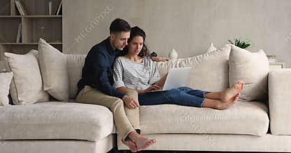 Couple sit on couch using laptop buy goods on internet