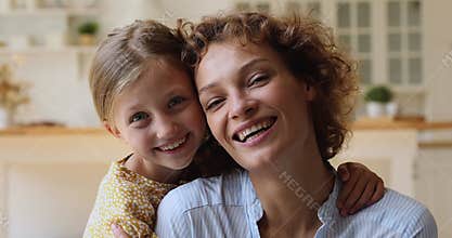 Little daughter piggybacks cheerful mom family smiling looking at camera