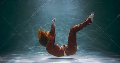 Cinematic side view of young beautiful woman slowly sinking deep under water. Depression, loneliness concept slow motion