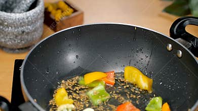 Closeup shot of adding colorful vegetables in a frying pan - cooking concept