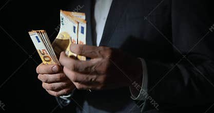 white collar crime - businessman counting euro banknotes on dark background. shadow economy money laundering and corruption