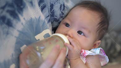Close up asian baby infant drinking milk from bottle in mother arm. woman embrace baby and feeding breast milk in bottle to newbor