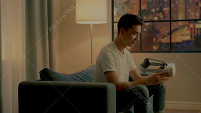 Asian guy looks at contemporary virtual reality glasses