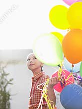 Young Girl Holding Up Balloons In Lawn