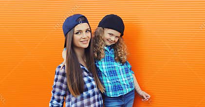 Stylish mother and child daughter together, happy mom with kid girl in casual clothing in the city