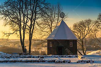 Scenic sunrise winter landscape of wooden chapel and snowy trees