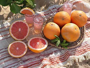 beach towel spread out on the sand, on which fruits and drinks lie